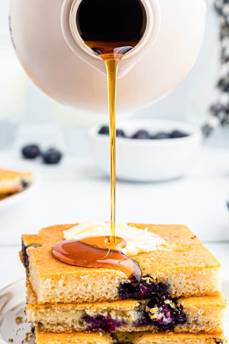 drizzling syrup on blueberry sheet pan pancakes