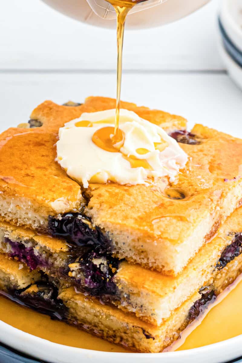 drizzling syrup on sheet pan blueberry pancakes