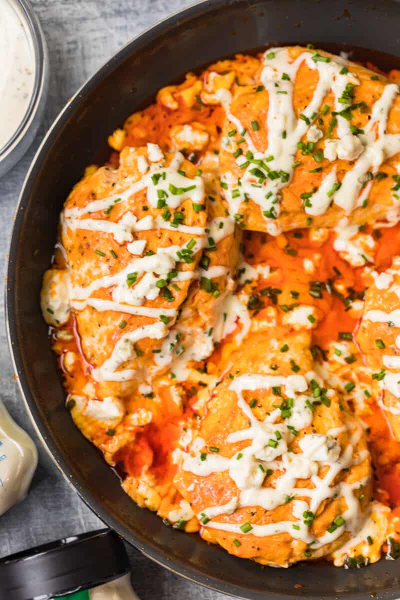 skillet with buffalo stuffed chicken topped with ranch and blue cheese