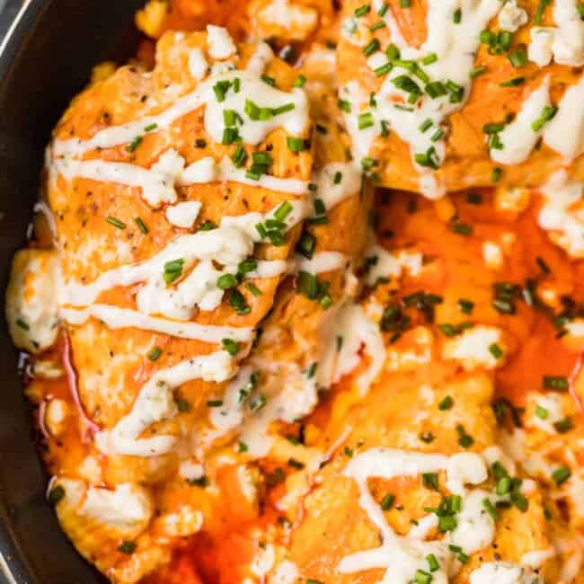 skillet with buffalo stuffed chicken topped with ranch and blue cheese