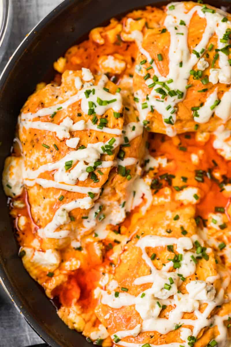 skillet with buffalo stuffed chicken topped with ranch and blue cheese