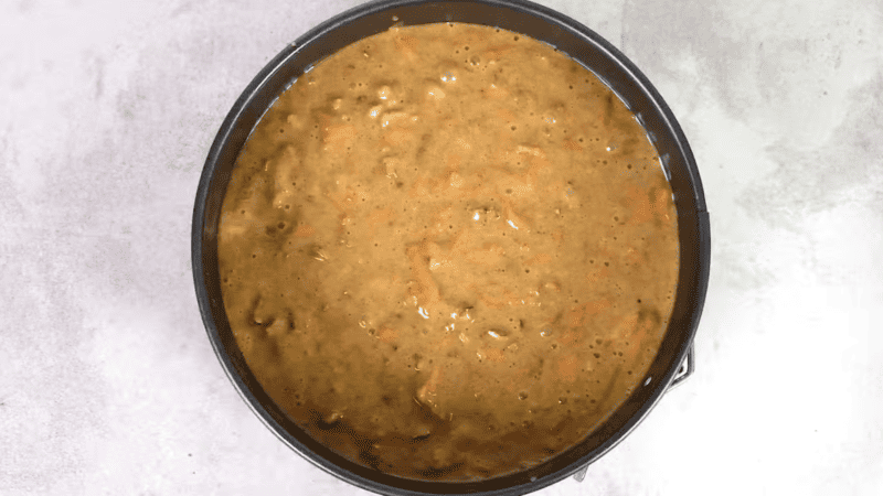 carrot cake batter in a round cake pan.