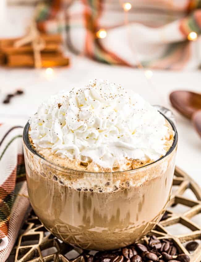 large clear mug with pumpkin spice latte topped with whipped cream