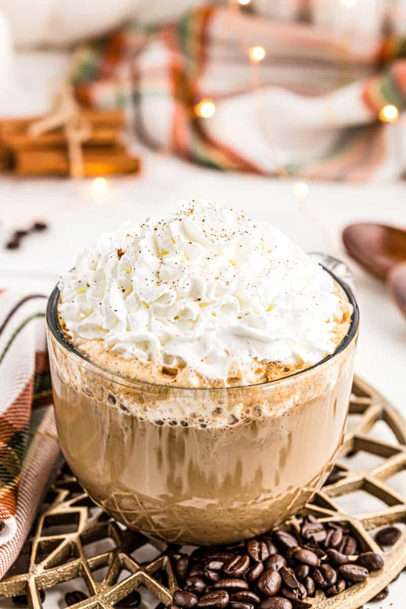 large clear mug with pumpkin spice latte topped with whipped cream