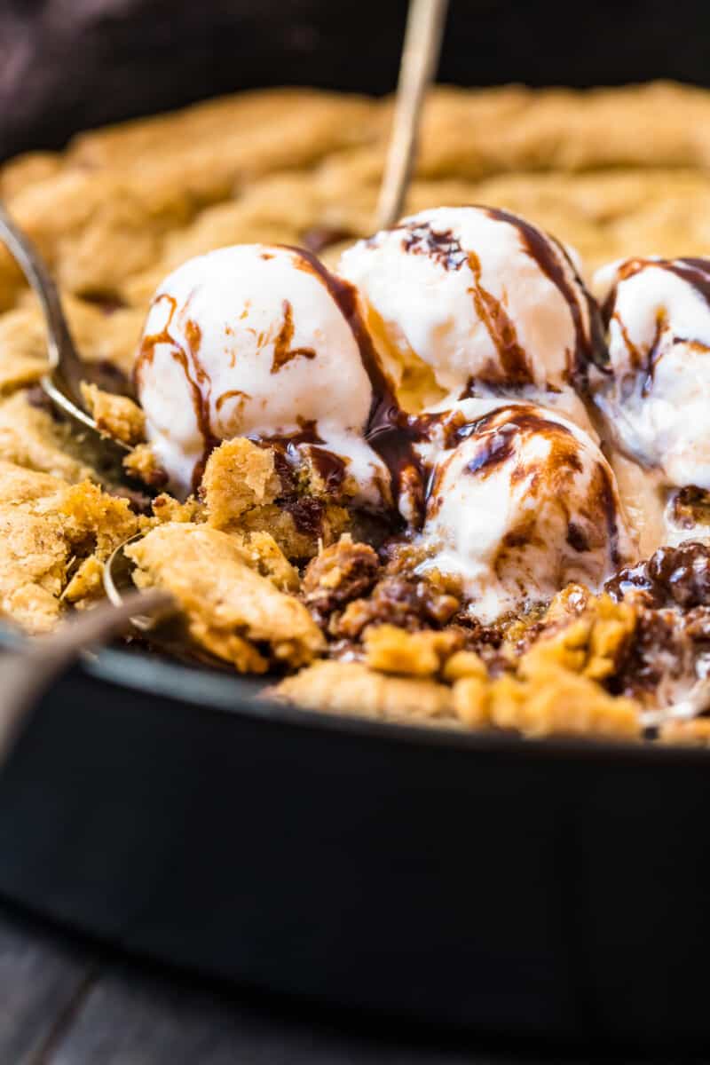 digging into skillet chocolate chip cookie with ice cream and syrup
