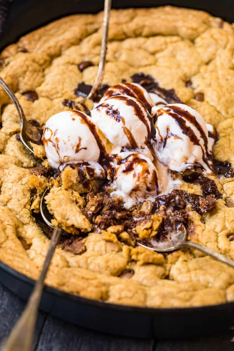 digging into skillet chocolate chip cookie with ice cream and syrup