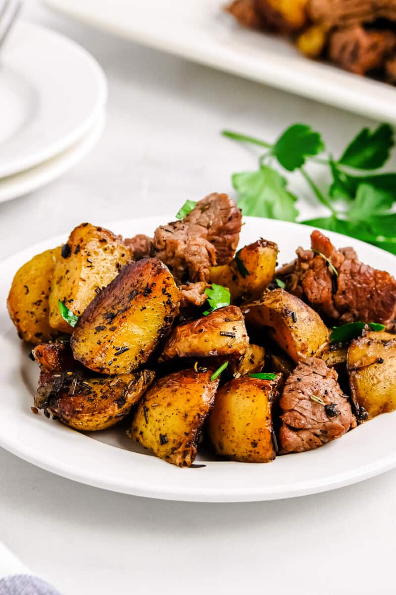 garlic steak bites with potatoes on white plate