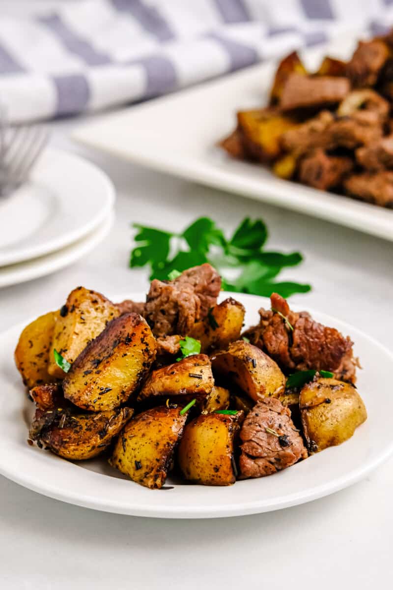 garlic steak bites with potatoes on white plate