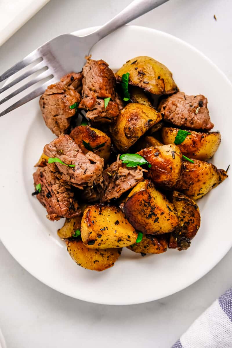 garlic steak bites with potatoes on white plate