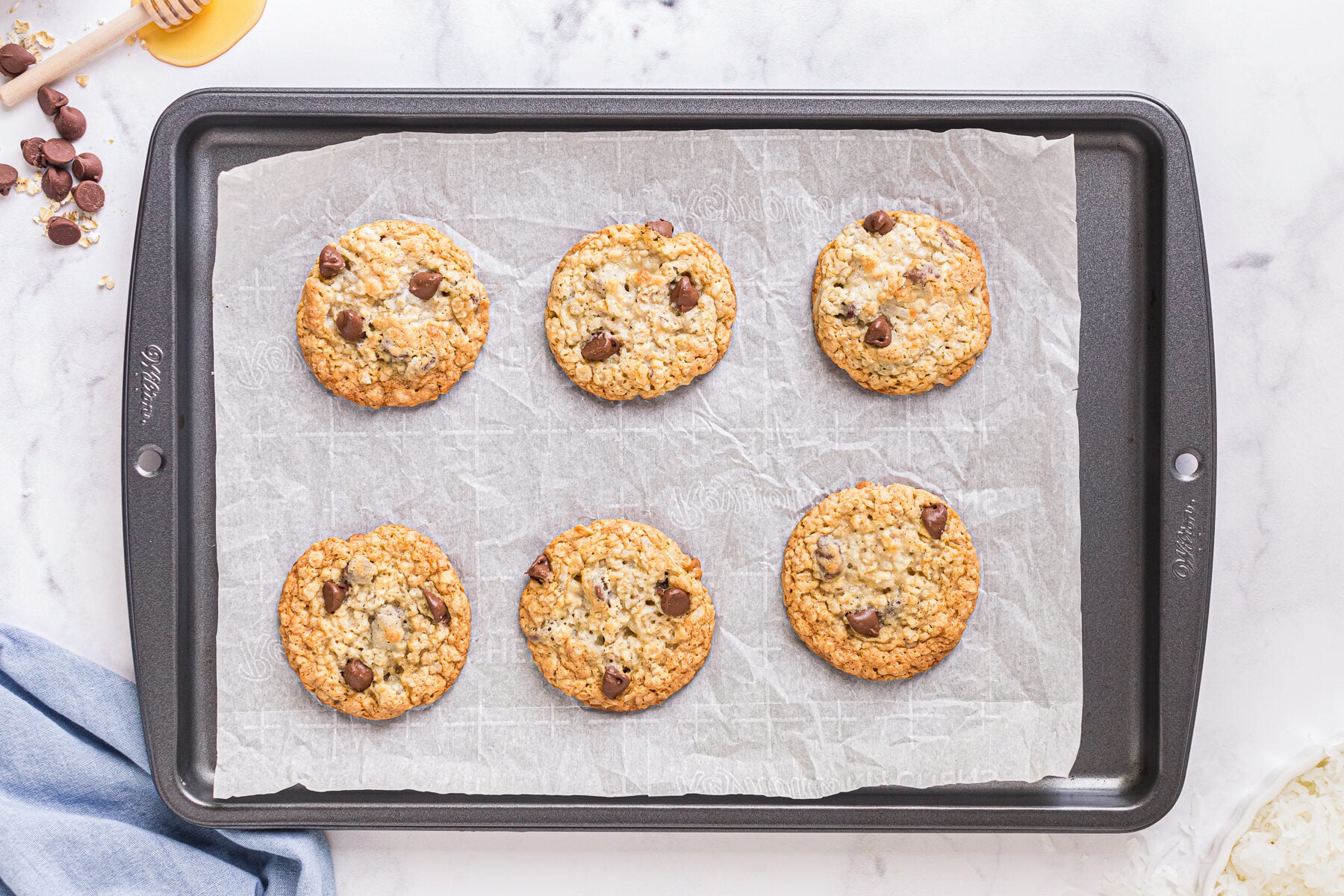 Baked oatmeal chocolate chip cookies on baking sheet, golden edges and soft centers