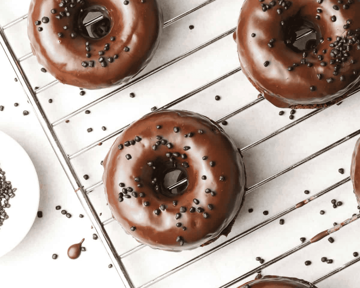 Chocolate glazed donuts on a cooling rack.