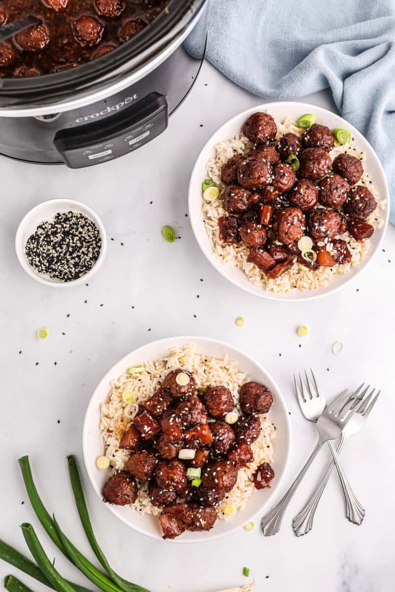 Two plates with teriyaki meatballs and rice.