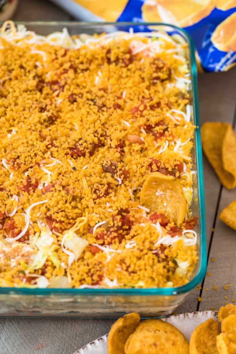Mexican layer dip with fritos in dish.
