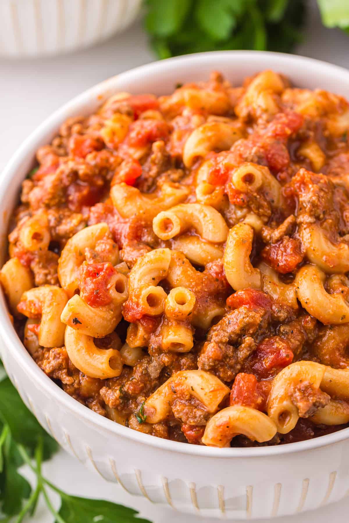a bowl of goulash, filled with macaroni noodles, ground beef, and tomatoes.