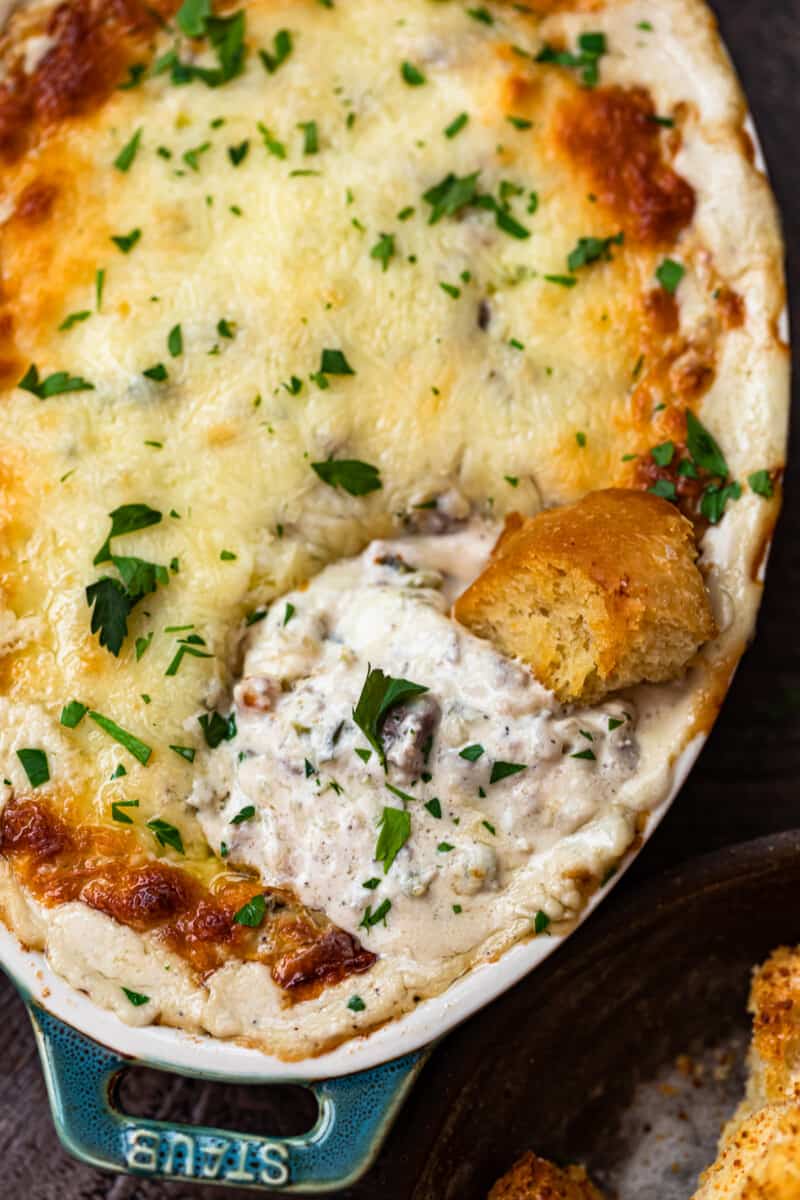 Philly cheesesteak dip in baking dish with bread dipper.