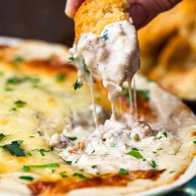 dipping toasted bread in philly cheesesteak dip