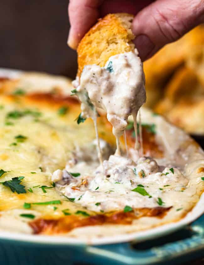 dipping toasted bread in philly cheesesteak dip