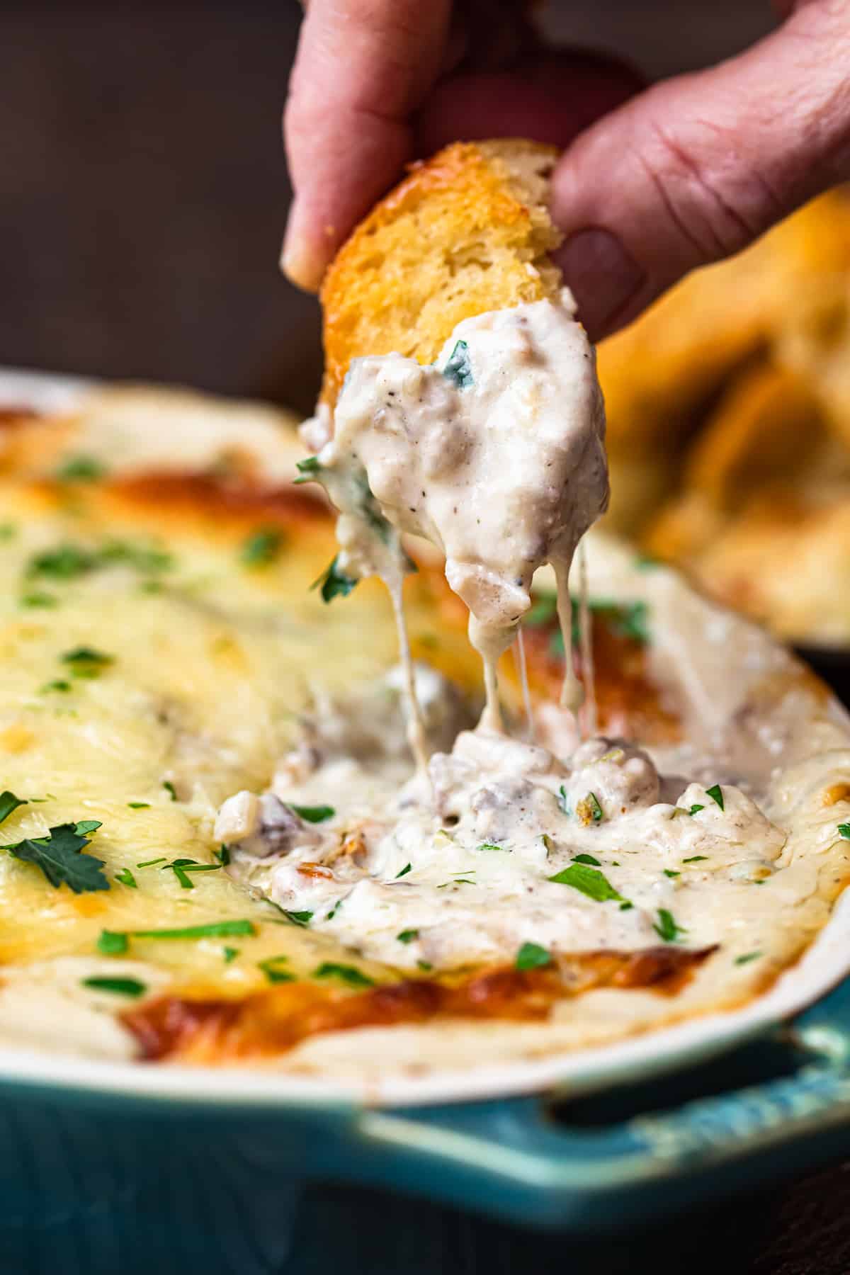 Dipping toasted bread in philly cheesesteak dip.