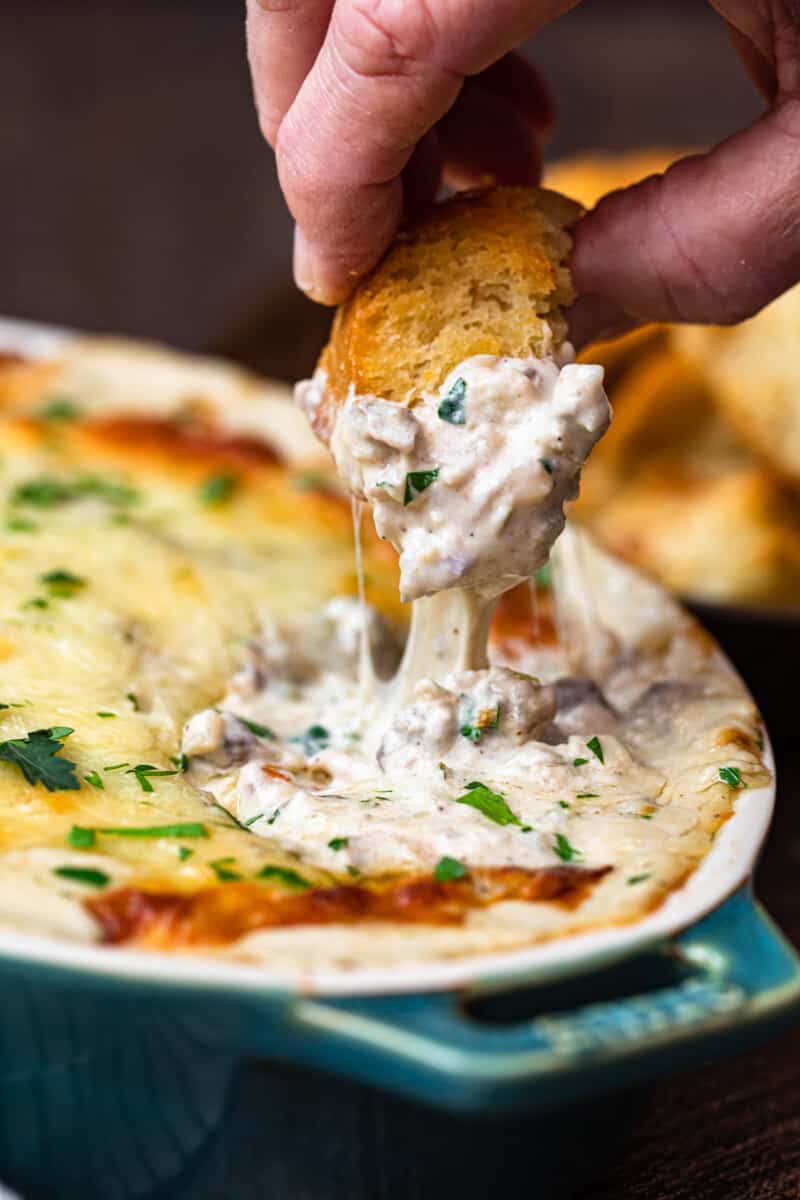 Dipping toasted bread in philly cheesesteak dip.