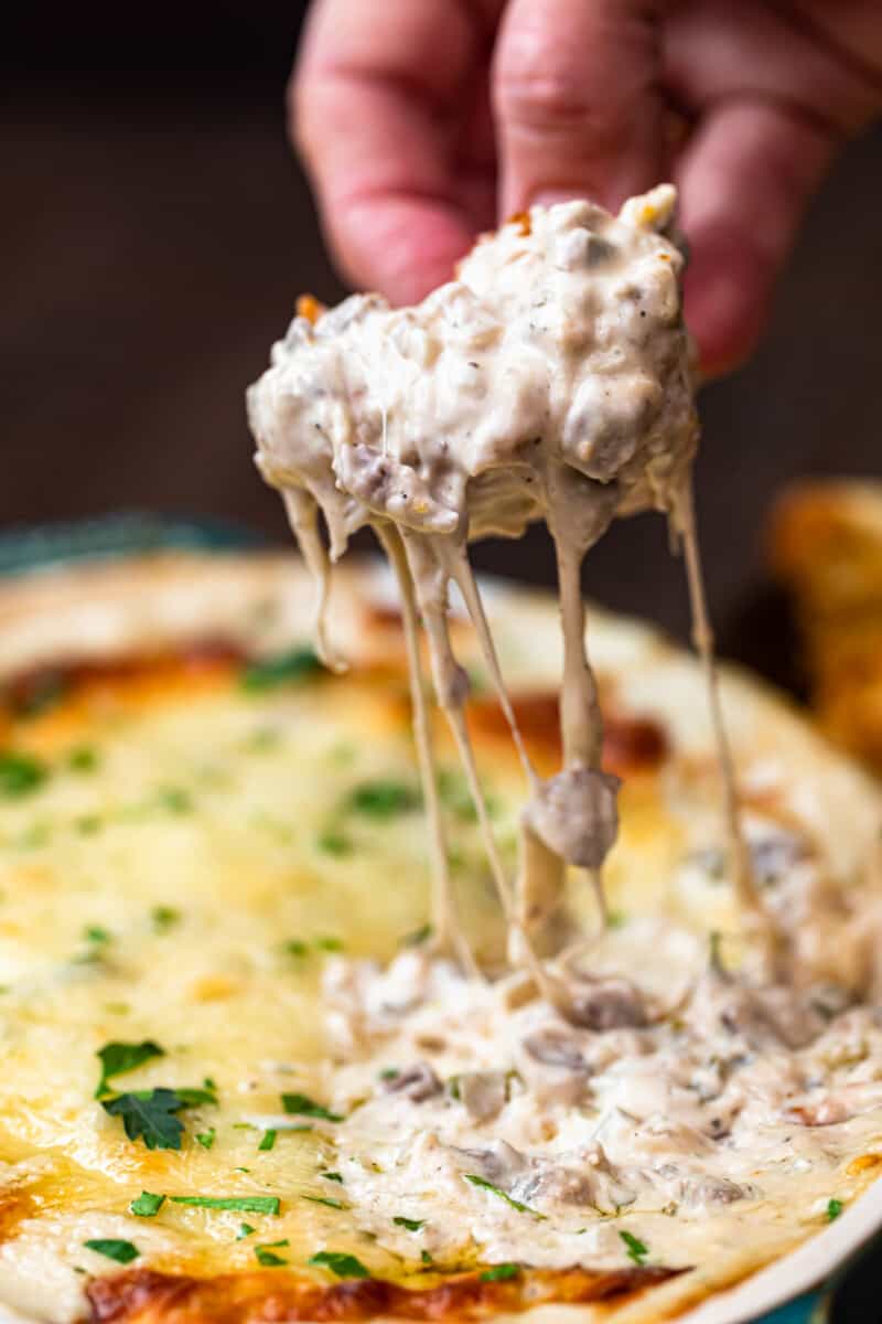 Dipping toasted bread in philly cheesesteak dip.