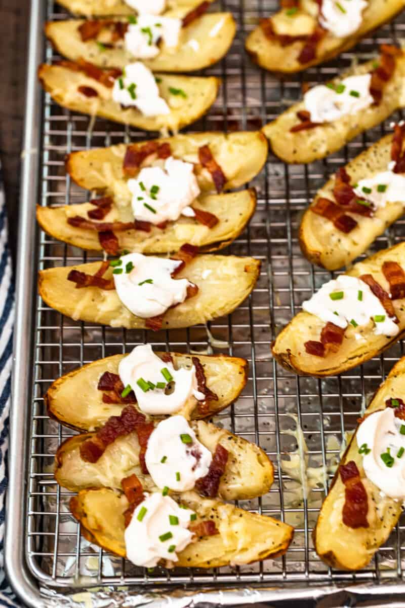 potato skins on baking sheet with sour cream, bacon, and chives