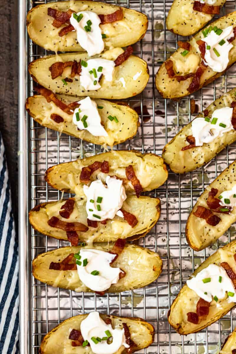 potato skins on baking sheet with sour cream, bacon, and chives