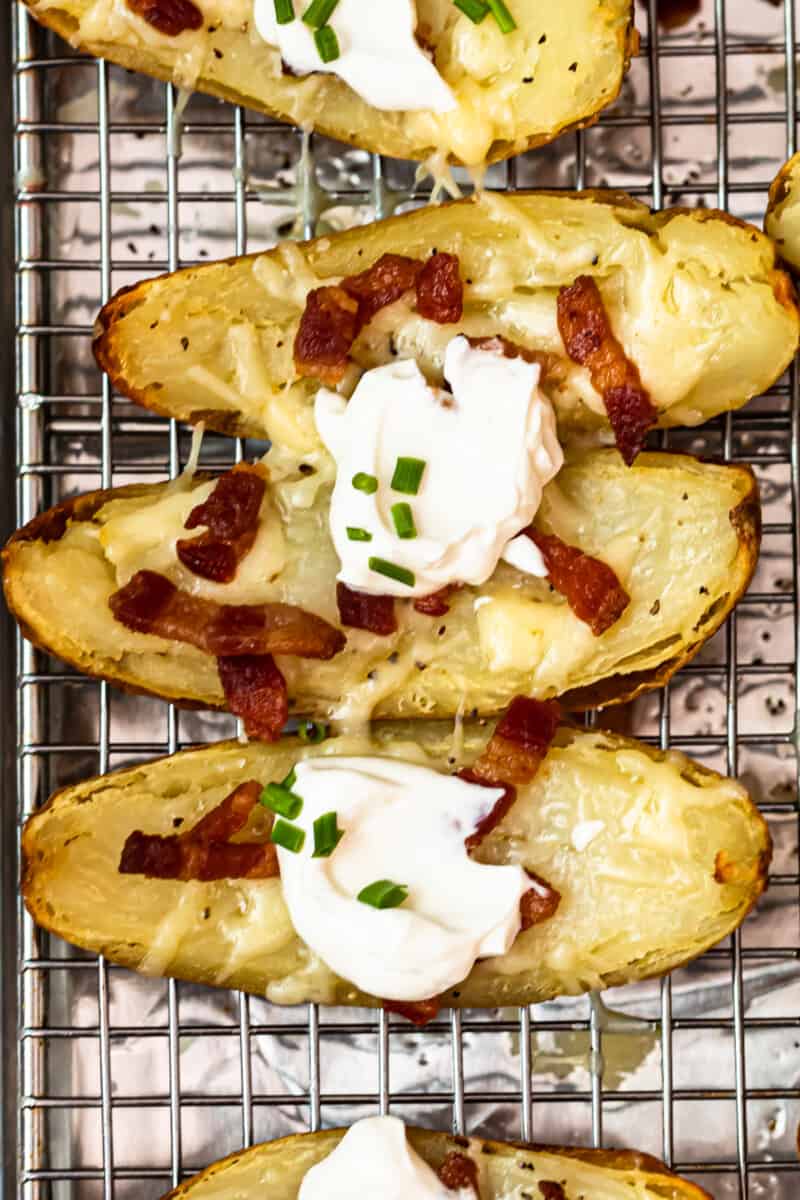 up close potato skins on baking sheet with sour cream, bacon, and chives