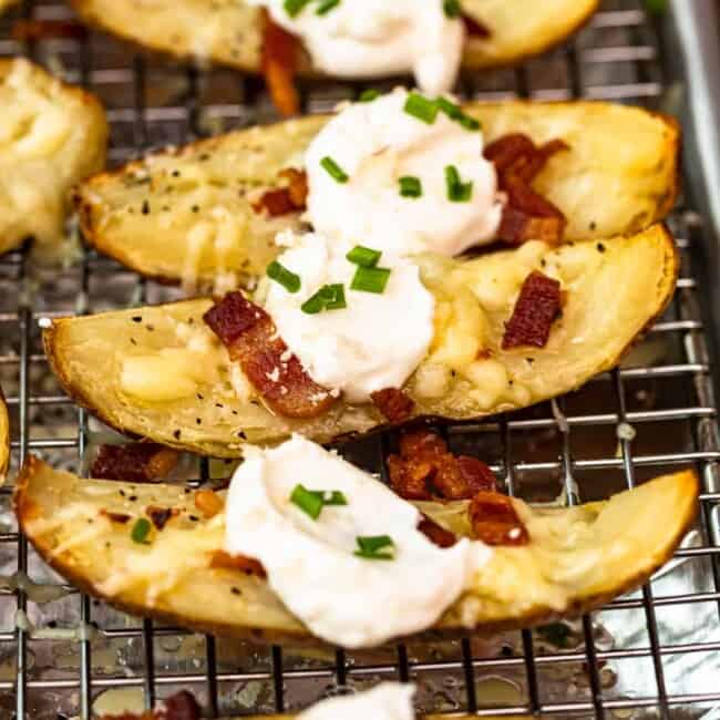 up close side shot potato skins on baking sheet with sour cream, bacon, and chives