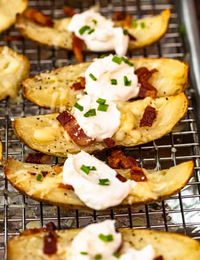 up close side shot potato skins on baking sheet with sour cream, bacon, and chives