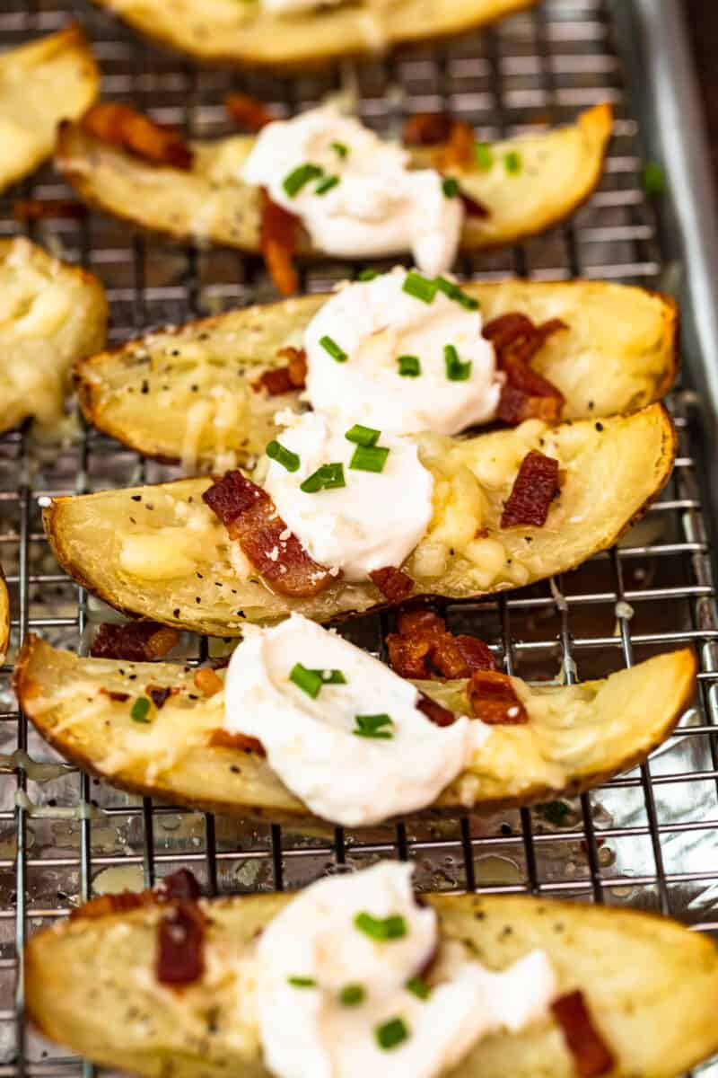 up close side shot potato skins on baking sheet with sour cream, bacon, and chives