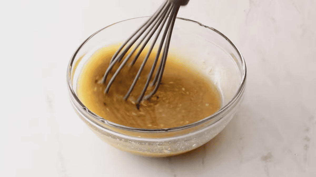 A whisk is being used to stir a turkey sliders mixture in a jar.