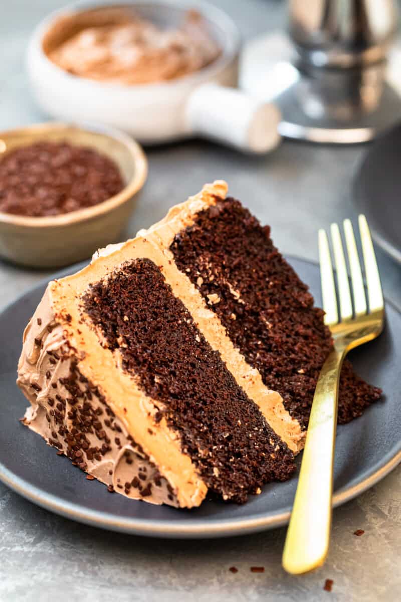 slice of chocolate cake with chocolate frosting on gray plate