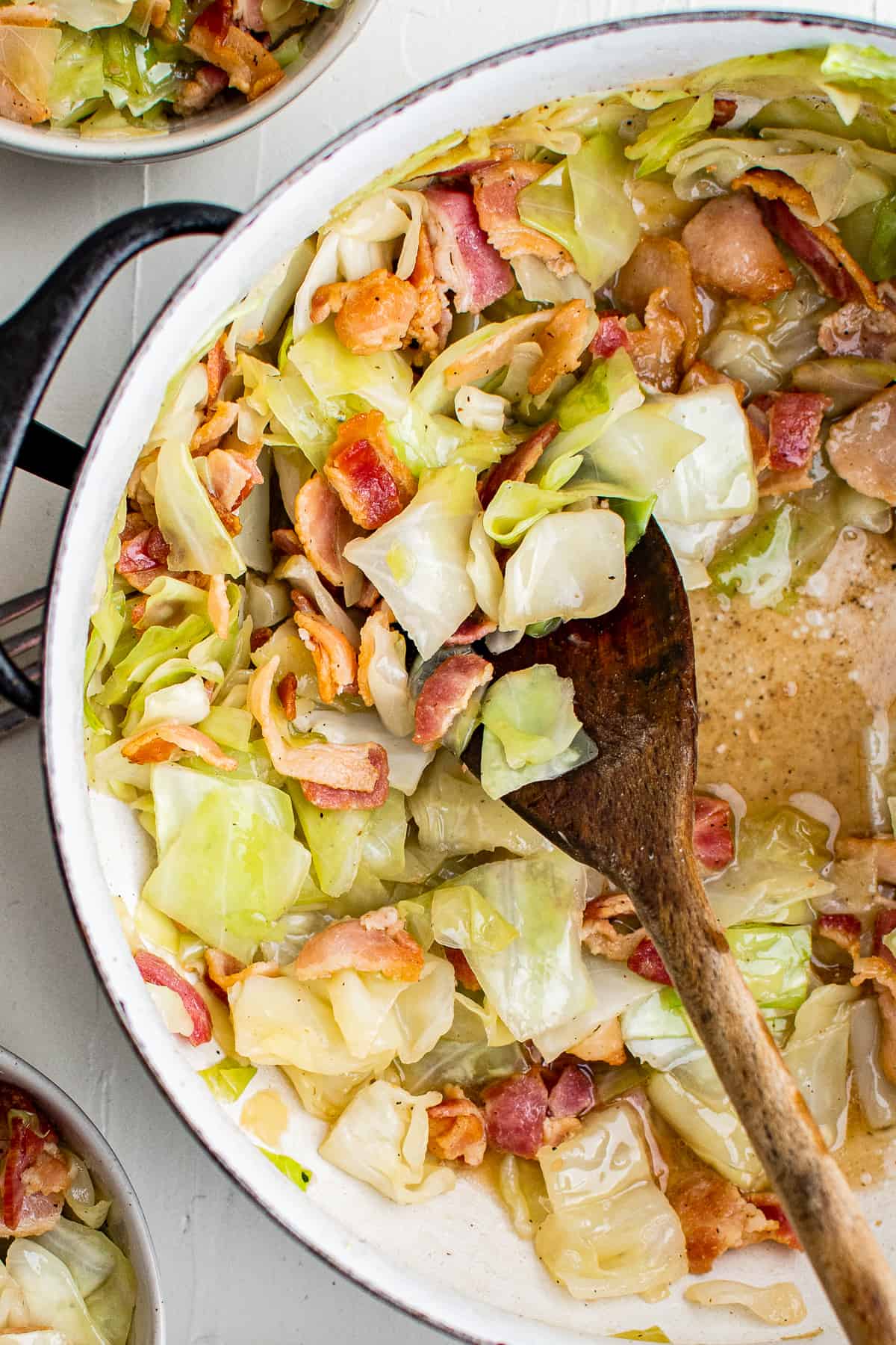 fried cabbage with bacon cooking in a skillet 