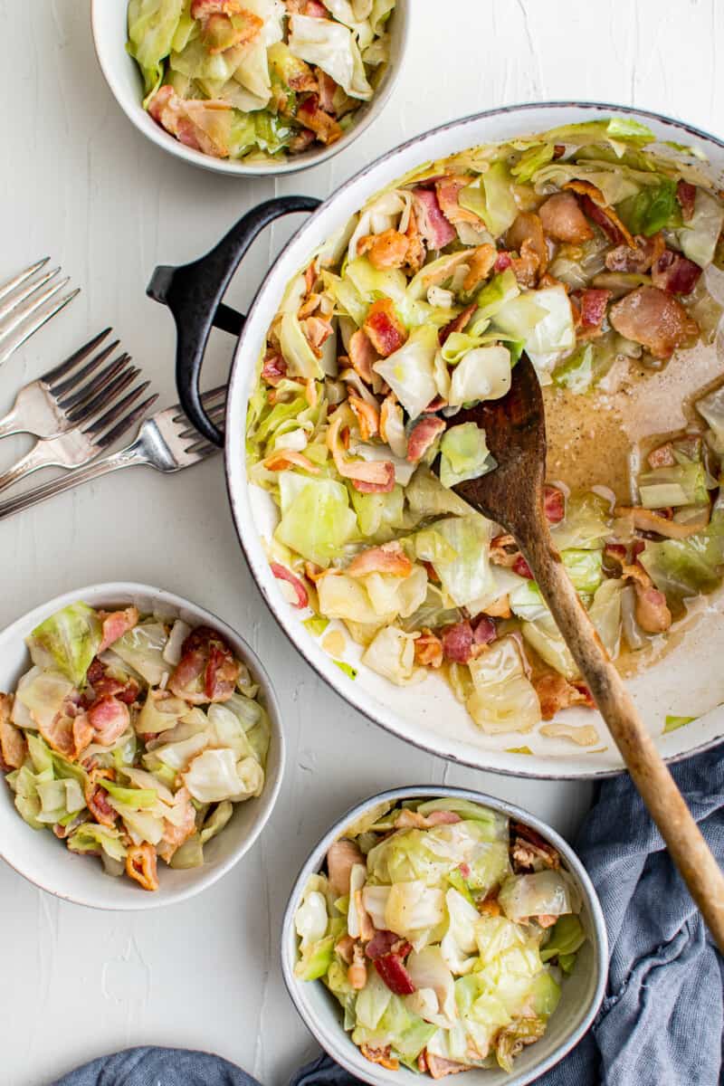 bowls of cabbage and bacon next to a pot full of fried cabbage