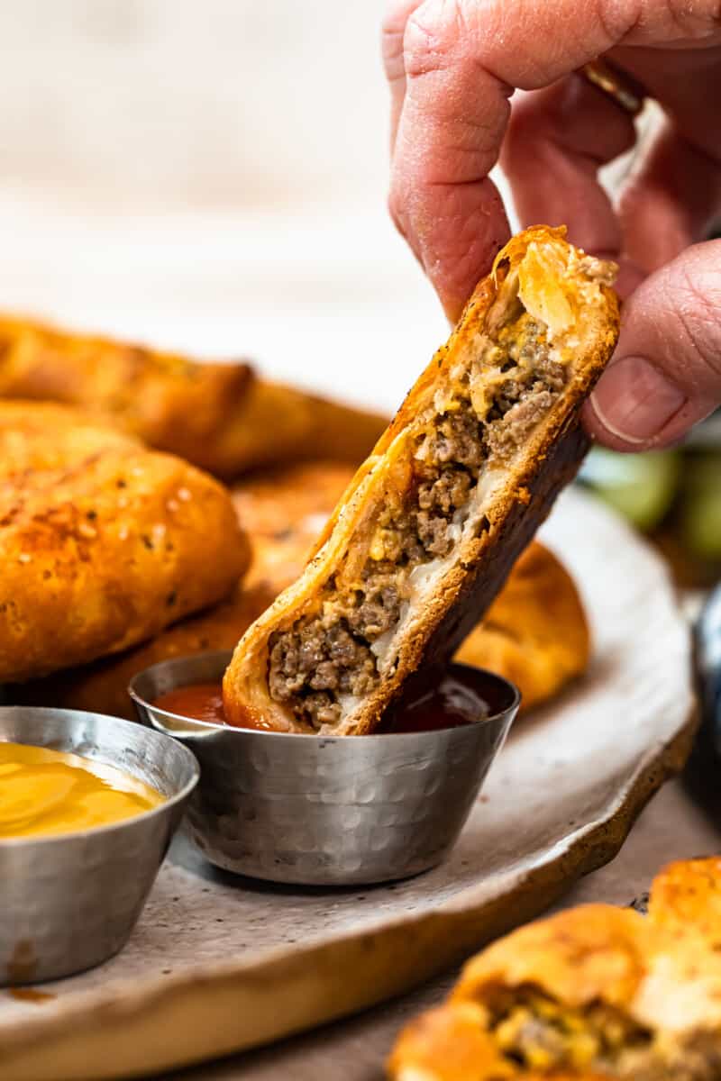 dipping cheeseburger hand pie in ketchup