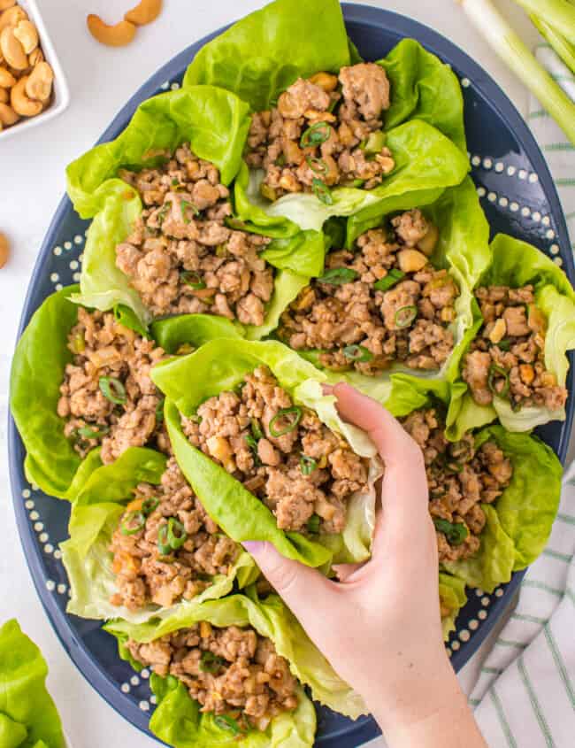 lifting up chicken lettuce wrap from platter