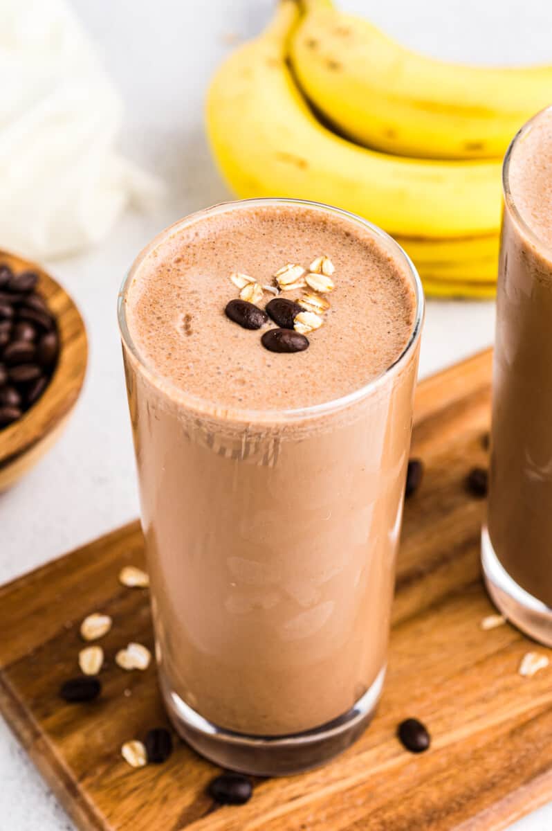 coffee smoothie in glass, with a bunch of bananas in the background