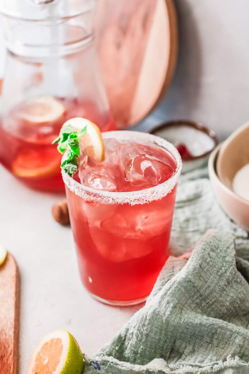 cup of cranberry margarita garnished with lime and mint