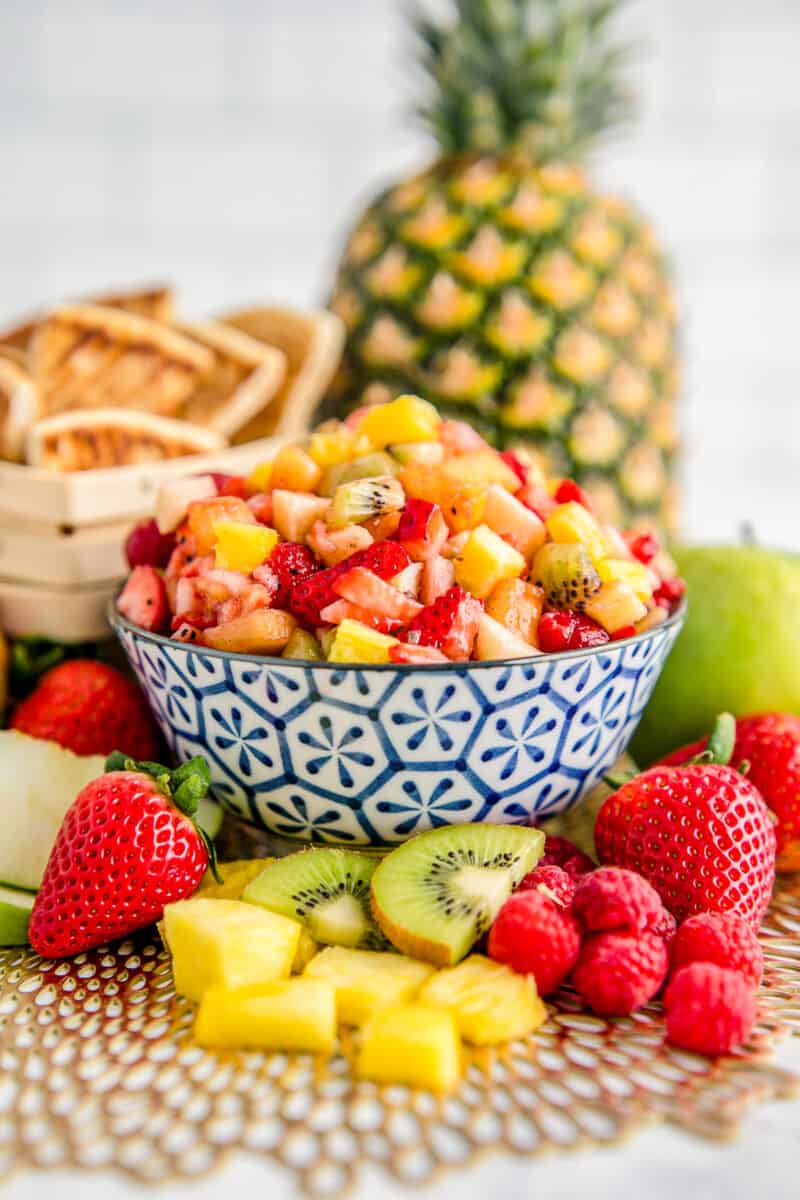 fruit salsa in a blue bowl surrounded by fruit