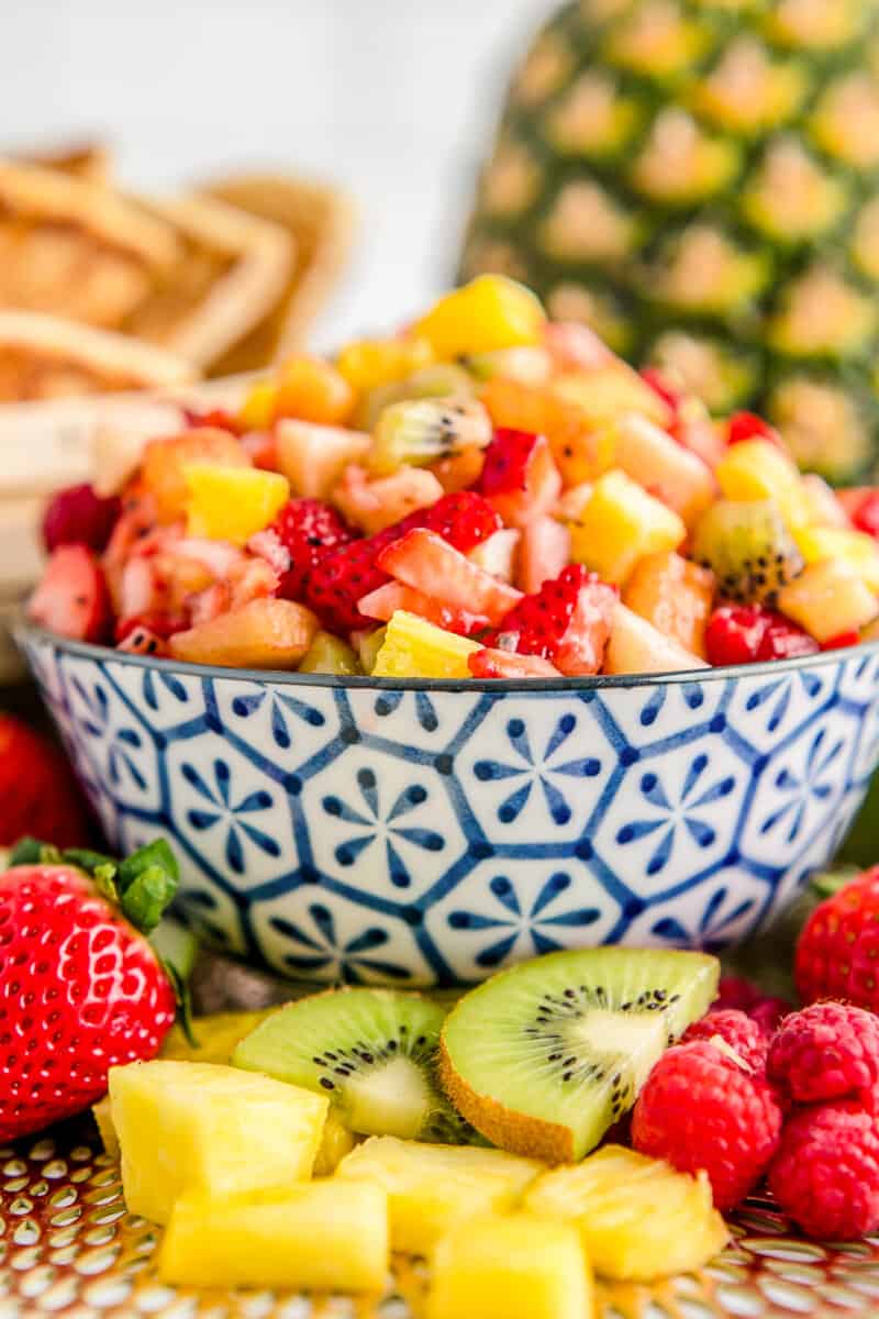 fruit salsa in a blue bowl surrounded by fruit