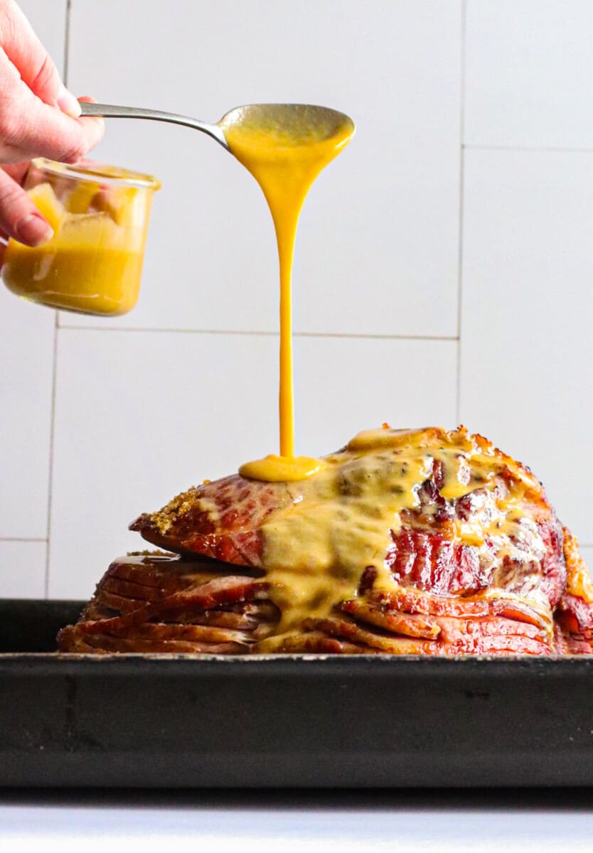 pouring honey mustard maple glaze on spiral ham