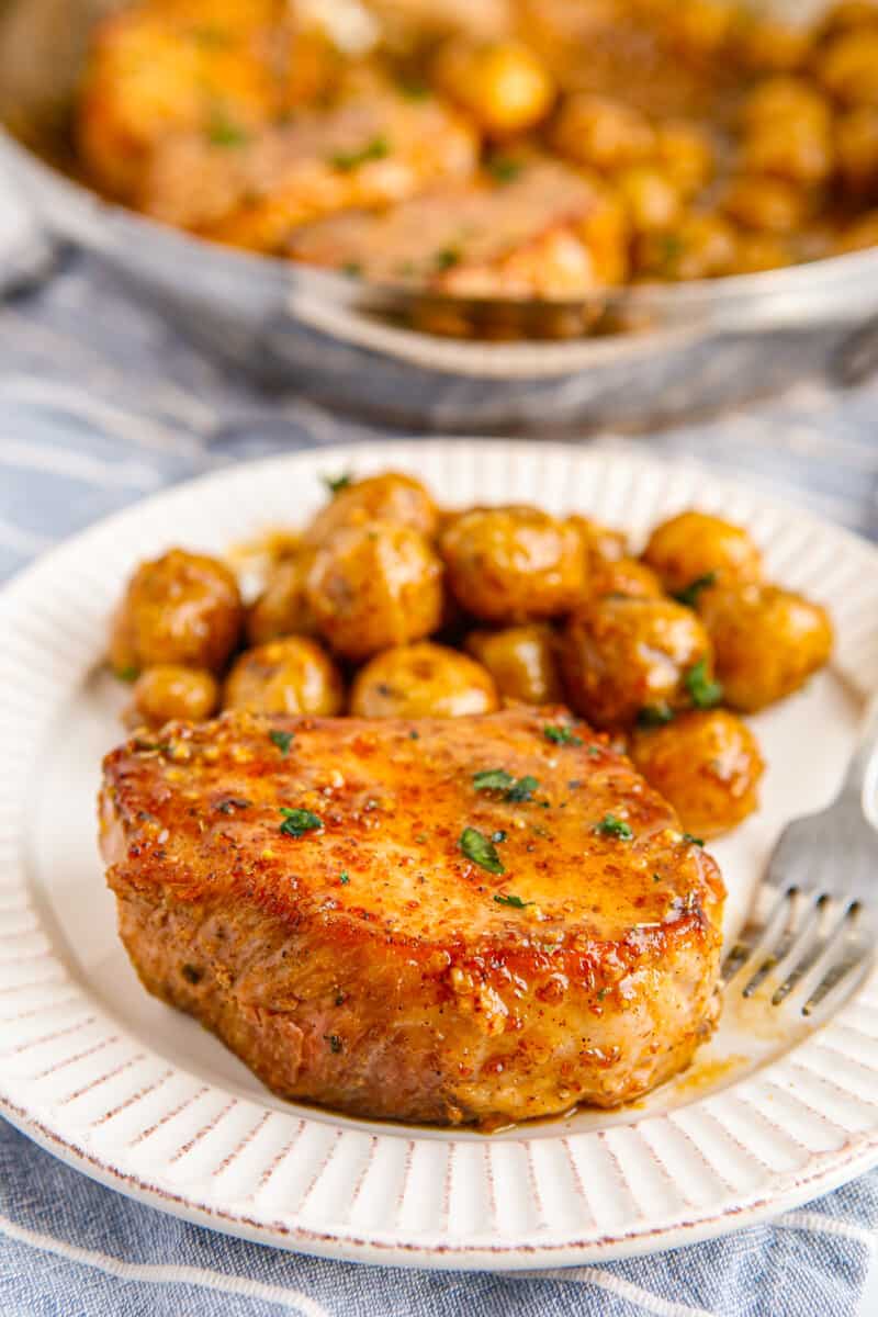 honey mustard pork chop with potatoes on white plate