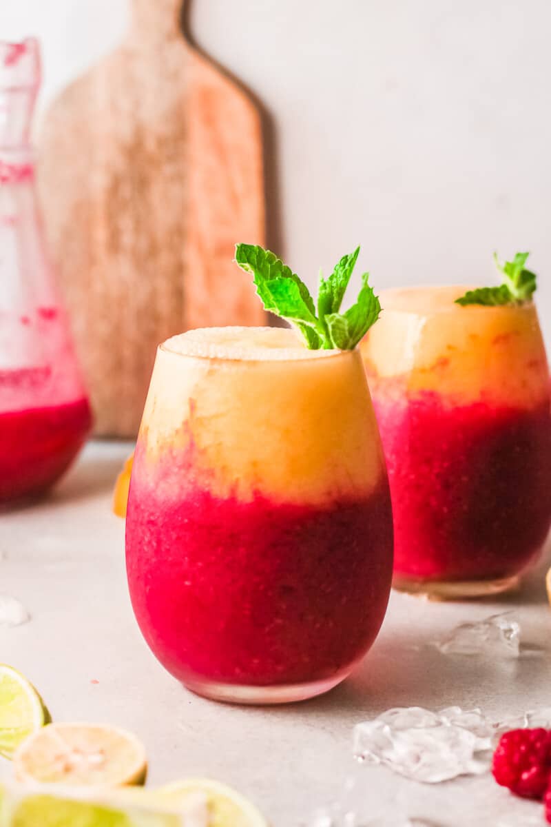 two glasses with layered raspberry mango daiquiris