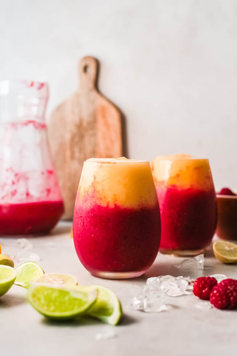 two glasses with layered raspberry mango daiquiris