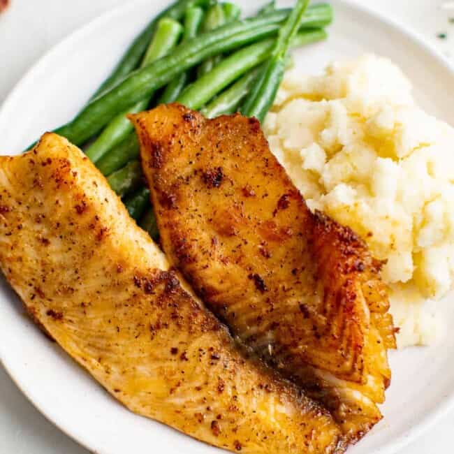 pan fried tilapia on plate with green beans and mashed potatoes