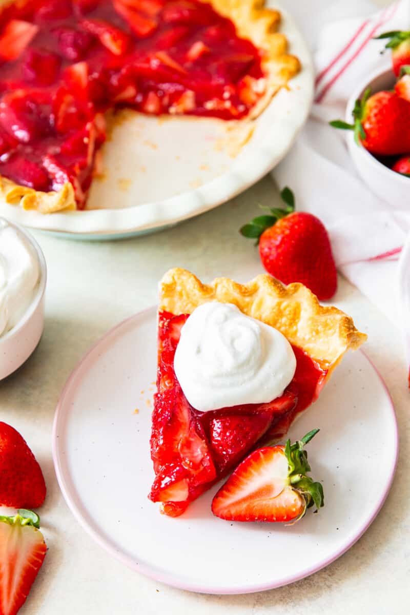 slice of strawberry jello pie with whipped cream next to full pie