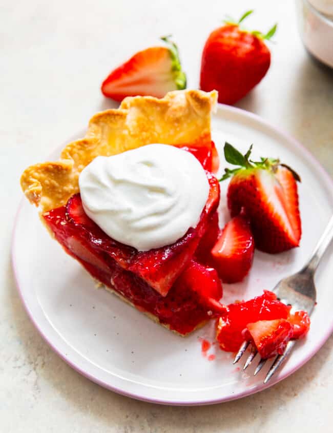 fork with bite out of slice of strawberry jello pie with whipped cream