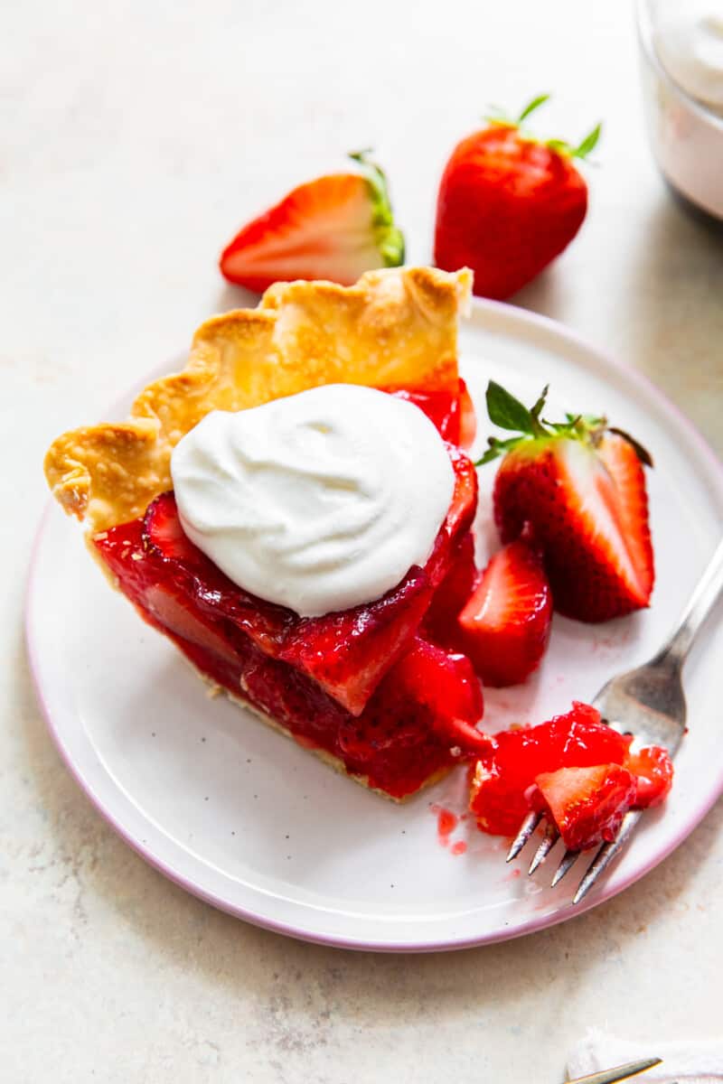 fork with bite out of slice of strawberry jello pie with whipped cream