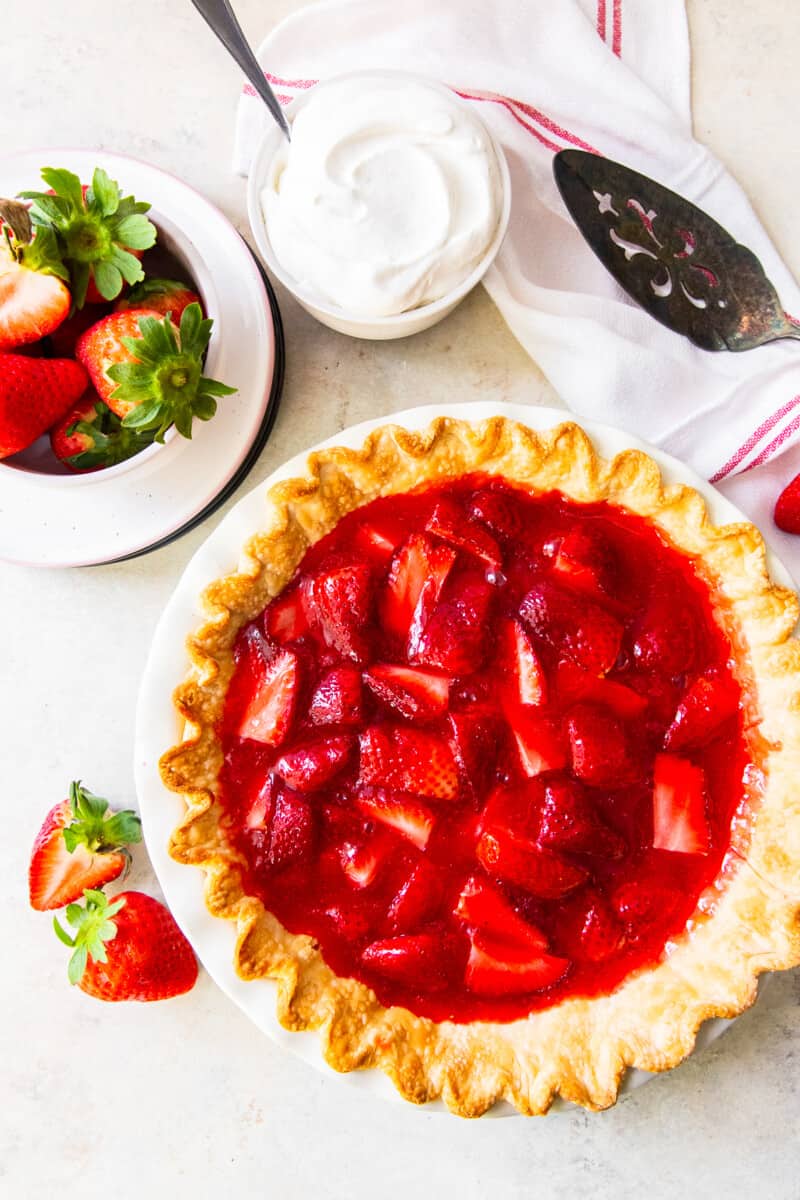 overhead strawberry jello pie next to strawberries and whipped cream