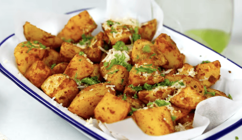 Air fryer potatoes on a plate with Parmesan and parsley.